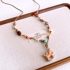 Detail of handmade wooden rocking horse pendant with vintage beads on a woven rope cord
