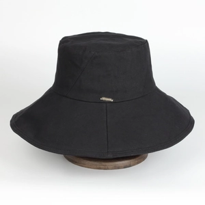 Close-up of wide brim black sun hat with golden metal plaque on a wooden stand