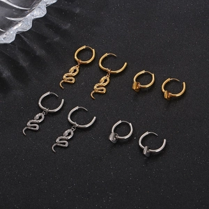 Détail de boucles d'oreilles serpent et perle en acier inoxydable bicolore sur fond noir