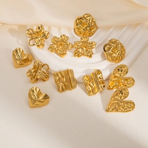 Detail of vintage heart and floral gold stainless steel earrings on white pedestal