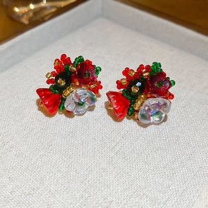 Macro shot of handmade beaded flower stud earrings in red and gold on jewelry box