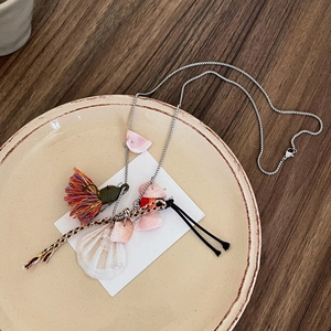 Macro detail of bohemian shell tassels and colorful string fringe on a silver chain