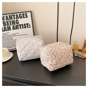 Detail of floral quilted cotton makeup bags in purple and red with zipper closure