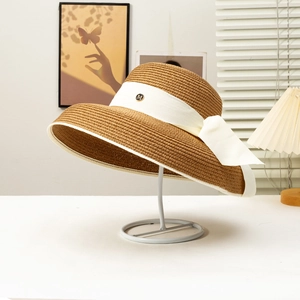 Detail of the golden M logo on the white ribbon of this vintage straw sun hat