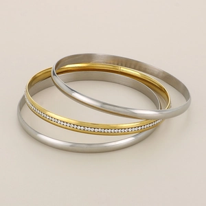 Detailed stack of gold diamond-set, brushed gold, and polished silver stainless steel bangles