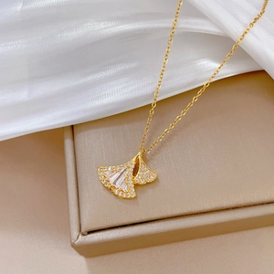 Elegant gold ginkgo leaf necklace with sparkling rhinestones on premium jewelry display