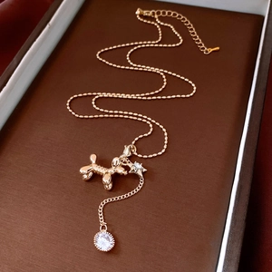 Close-up of golden balloon dog pendant with a sparkling zircon drop on a beaded chain
