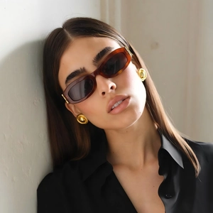 Close-up of elegant gold swirl textured round earrings on model with retro sunglasses