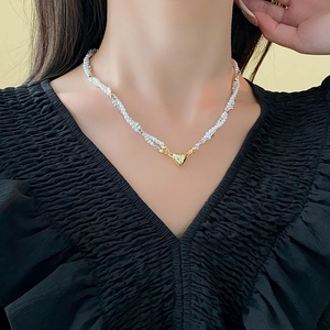 Detail of silver beads and pearl necklace with a gold magnetic heart pendant on a model