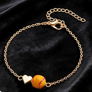Détail d'un bracelet de baseball doré avec pendentif cœur et perle sur velours noir