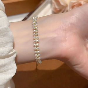 Detail of double-layer bracelet with white pearls and gold beads on lace sleeve