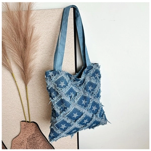 Close-up of denim tote bag with star embroidery and distressed fringe edge detail