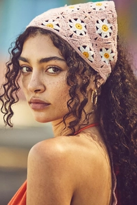Close-up of handmade pink crochet headscarf with white daisy patterns in a bohemian style