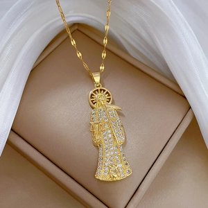 Golden Santa Muerte pendant with sparkling stones and sickle on a soft textile background