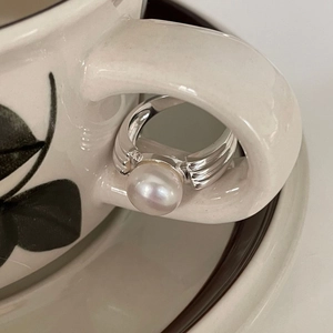 925 silver pearl ring with wavy band texture hanging on a ceramic cup handle