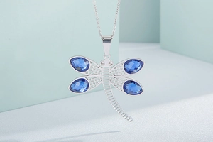 Detailed macro view of dragonfly pendant with blue crystal teardrop wings and silver metal