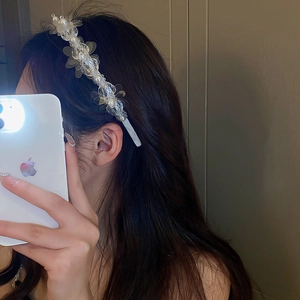 Detail of white pearl and flower headband worn on hair, showing elegant texture