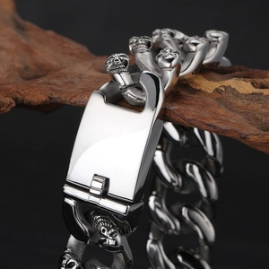 Double row skull stainless steel bracelet for men displayed on textured driftwood