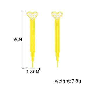 Detailed view of long gold tassel earrings with heart design and white zircons