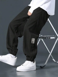 Detail of black corduroy cargo pants featuring ribbed texture and cuffed hem design