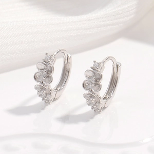 Macro de boucles d'oreilles fleur en argent avec zircons sur tissu blanc