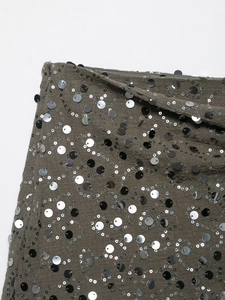 Macro di paillettes argento su tessuto grigio scuro con dettagli di cucitura fine