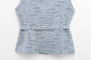 Close-up of blue and white tweed vest fabric with woven texture and matching belt detail