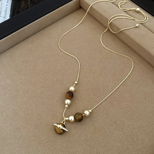 Detail of vintage horse necklace with brown tiger eye stone, pearl, and gold planetary pendant
