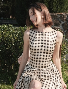 Detail of gingham check pattern and decorative white buttons on a sleeveless summer dress