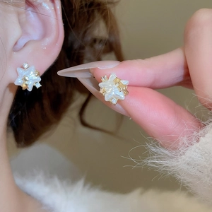 Détail d'une boucle d'oreille étoile dorée à l'or 14 carats avec nacre et zircons