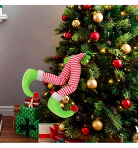 Christmas elf legs decor with red white stripes and green shoes on a festive tree