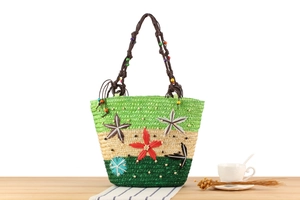 Détail du sac cabas bohème en paille avec broderies d'étoiles de mer et anses en perles