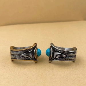 Détail macro d'une bague vintage en acier avec turquoise et motifs de plumes gravés