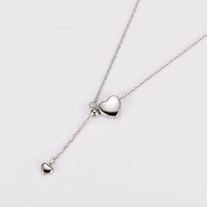 Macro view of silver Y-shape lariat necklace with double heart-shaped pendant charms