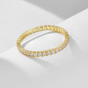 Close-up of gold-plated eternity ring featuring micro-pave cubic zirconia on a white block