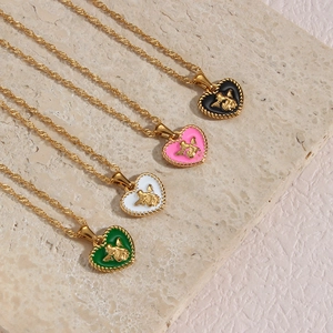 Detail of four gold heart necklaces with angel reliefs and colorful enamel on marble