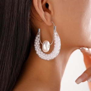 Detail of U-shaped mesh earrings with white beads and oval faux pearl on model