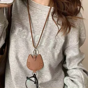 Détail du support de lunettes en cuir marron en forme de chat avec cordon fin en cire