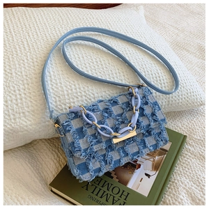 Détail du sac à bandoulière en denim bleu à carreaux avec franges et chaîne acrylique