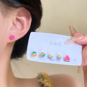 Detailed view of rainbow resin flower and heart studs on an earlobe and display card