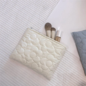 Close-up of quilted floral embroidery and soft texture on the cream puffy vanity bag