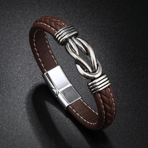 Detailed close-up of brown braided leather bracelet with silver knot and white stitching