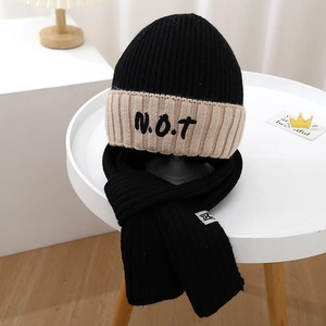 Close-up of knit winter set for boys featuring a NOT logo hat and matching black scarf