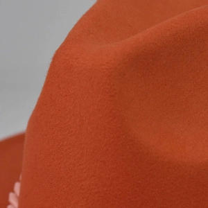 Macro detail of the orange felt fedora showing the thick texture and wool-blend material