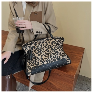 Detail view of leopard print tote bag featuring black studs and tassel charm detail