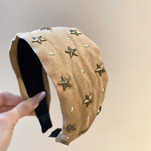Détail d'un serre-tête en tissu orné d'étoiles en bronze et de petits rivets ronds