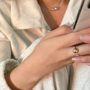 Detailed close-up of a minimalist silver open ring with dual bead spheres on model hand