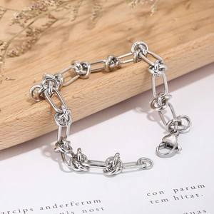 Detailed macro shot of a silver knot-designed metal chain bracelet with a lobster clasp
