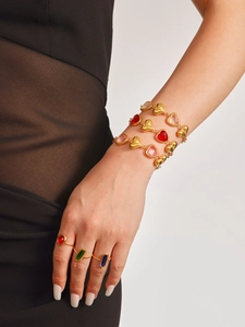 Detalle de pulseras de corazón en acero bañado en oro 18k y anillos de piedras de colores