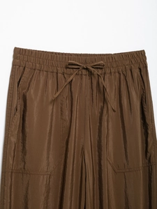 Close-up of brown safari trousers featuring elastic drawstring waist and large cargo pockets